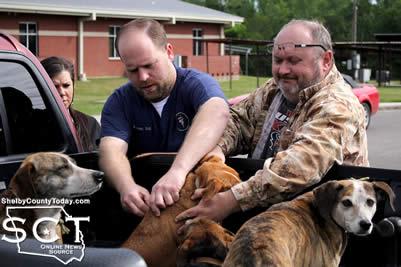 Dr. Jousan is seen giving vaccines to hunting dogs of Lynn Johnson (right).