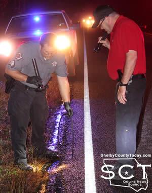 Shelby County Sheriff's Deputy Michael Griffin and Investigator Kevin Windham search both sides of the roadway for evidence of the incident.