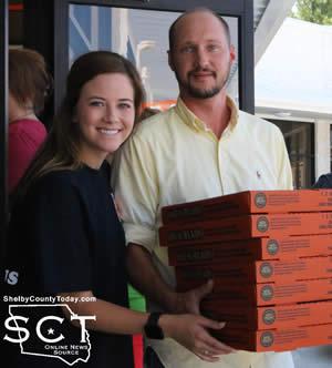 Mary Caroline of Little Caesars helps Joshua Moody carry out pizza.