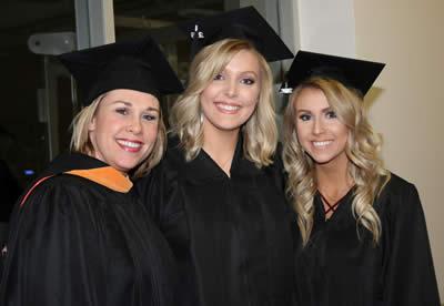  Nursing instructor, Ashley Brewster, congratulates two nursing program graduates.