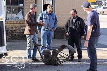 Dennis Leggett (middle) is seen with Mike Wolfe (left) and Frank Fritz (black jacket) and a film crew member (blue shirt) as they discuss an old motorcycle frame in between filming.