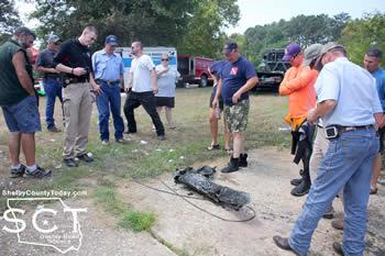 Authorities are seen looking at the vehicle bumper which was brought to the surface from Toledo Bend.