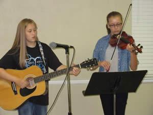 Alana Scull and Hannah Menefee played a number of classical pieces and religious songs for the Golden Harvest Ministries meeting. Hannah played her violin and Alana changed from the violin to a guitar and to a mandolin. Susan Scull came with the girls to care for technical details.