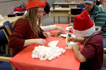 Laura Poynor, Stephen F. Austin State University senior and Braille and Cane Club president, along with SFA student Trenton Rowland help children build Santa beards during a holiday celebration in SFA’s Human Services Building.